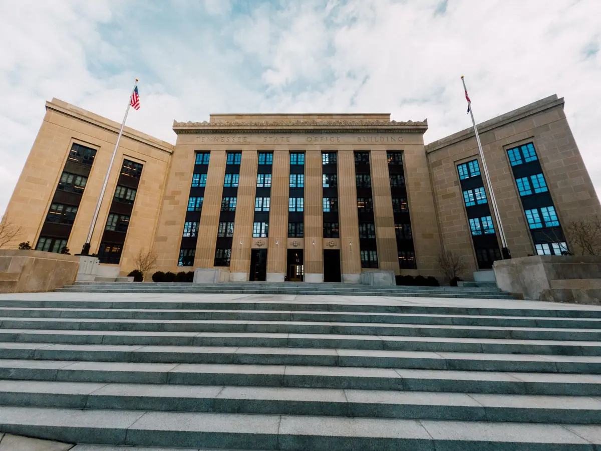 A stone government building with flags above a wide flight of steps